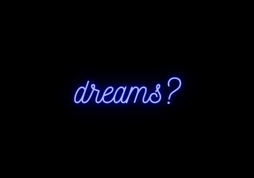 Glowing, neon indigo text on a black background that says, "dreams?"